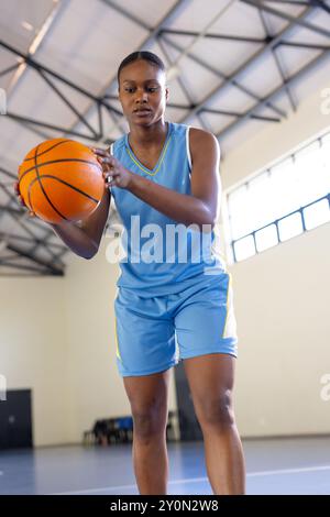 Gioca a basket, donna in abbigliamento sportivo che si concentra sul dribbling in campo coperto Foto Stock