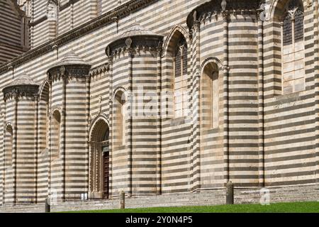 Pareti laterali del Duomo di Orvieto con strati alternati di pietra bianca e nera Foto Stock