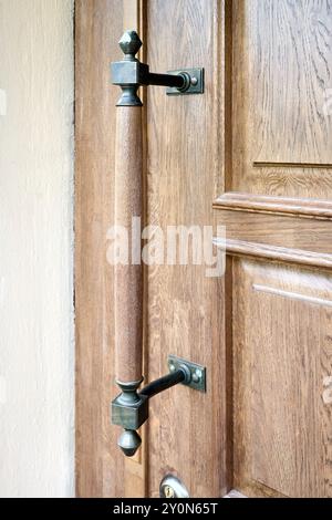 Porta in legno con elementi forgiati focalizzazione selettiva su vecchia porta in legno marrone con spazio immacolato, scatto verticale. Foto Stock