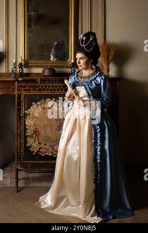 Bella giovane donna vestita in stile rococò Maria Antonietta e con un'autentica parrucca che posa all'interno di un castello francese Foto Stock