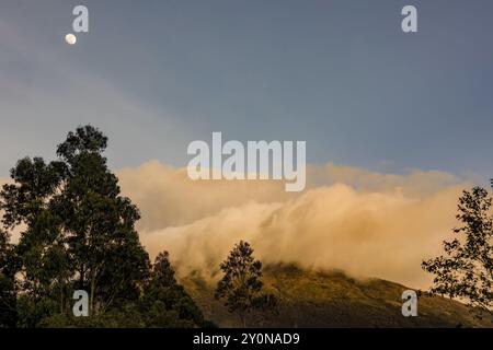 La luna quasi piena sorge sul monte Iguaque, nelle Ande orientali della Colombia centrale, su un cielo limpido e fatato al tramonto. Foto Stock