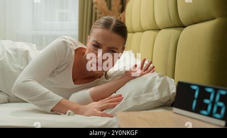 Stanco sonnolento affaticato ragazza svegliarsi nel letto di prima mattina casa camera da letto stressato insoddisfatto turbato tempo pigro andare al lavoro insonnia problema di salute sonno Foto Stock