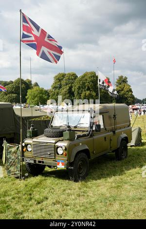 Un Land Rover Defender dell'esercito britannico sotto un Union Jack a una fiera nazionale. Foto Stock