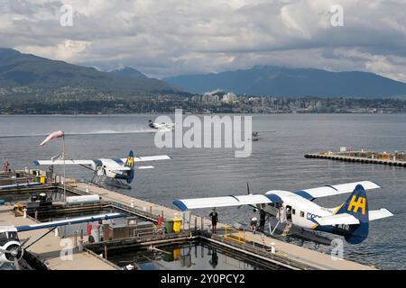 Vista verso nord dal terminal degli idrovolanti a Coal Harbour con un atterraggio aereo sull'acqua, la North Shore e le montagne sullo sfondo. Foto Stock