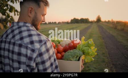 Uomo uomo di successo Guy agricoltore caucasico shopper uomo d'affari agricolo cliente mani che trasporta scatola casse verdure cibo passeggiate campo Foto Stock