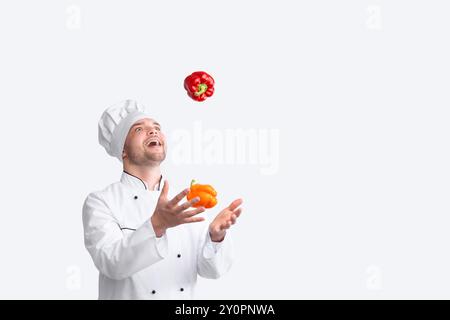 Excited Chef Man Juggling Sweet Peppers In Piedi In Studio, Panorama Foto Stock