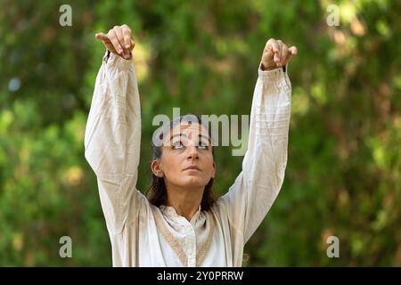 La giovane donna in costume d'epoca è all'aperto in un ambiente forestale, eseguendo una scena teatrale Foto Stock