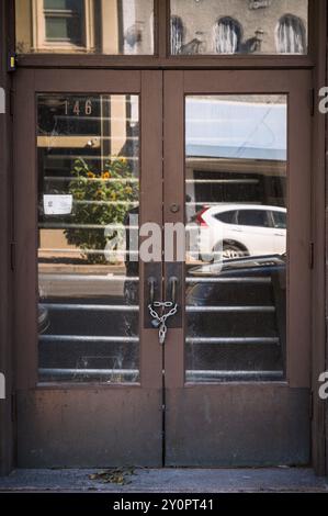 Una porta concatenata e chiusa a lucchetto su una piccola strada principale della città. Foto Stock