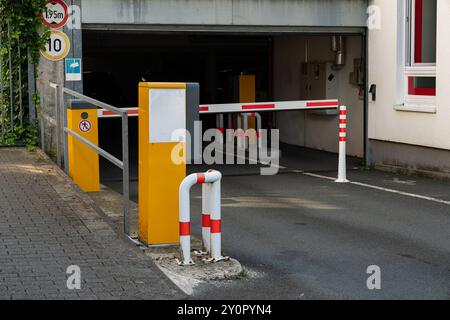 Accanto a un parcheggio sotterraneo si trova un cancello giallo e bianco con barriere a strisce rosse. Foto Stock