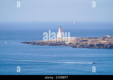 Faro del XVIII secolo a Tarifa Point, con traghetto in arrivo nel porto, Andalusia, Spagna. Foto Stock