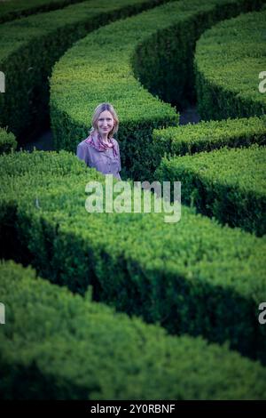 Una donna si trova in un labirinto di siepi verdi in un vecchio parco europeo. Foto Stock