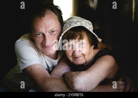 Un ritratto caldo e accogliente di un uomo che abbraccia sua nonna. Foto Stock