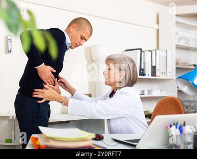 L'uomo che lamenta di mal di stomaco al medico maturo della donna Foto Stock