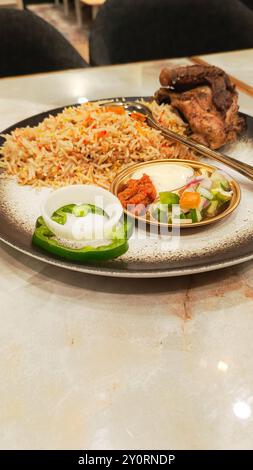 Ritratto semi-primo piano del riso kebuli (nasi kebuli), tipico cibo arabo su un tavolo con spazio vuoto accanto, angolo inferiore Foto Stock