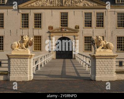 Elegante residenza storica con statue di leoni e timpano decorativo, accessibile tramite un ponte, dornum, frisia orientale, germania Foto Stock