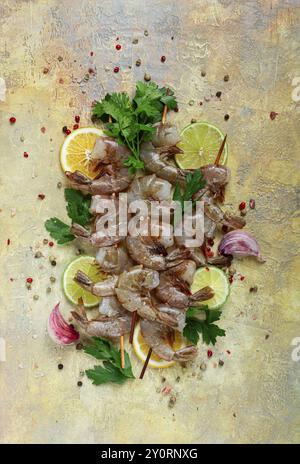 Gamberi crudi su spiedini, kebab di gamberi, fette di lime e limone, spezie ed erbe aromatiche, vista dall'alto, senza persone Foto Stock