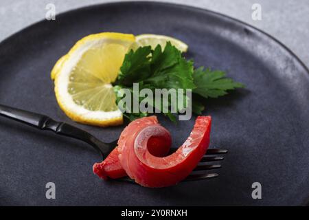 Salmone salmone affumicato freddo, su una forchetta, con limone e prezzemolo, vista dall'alto, primo piano, nessuno Foto Stock