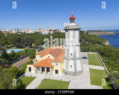 Un faro con una cima rossa accanto a un edificio con vista sulla foresta e sul mare, vista aerea, Farol da Guia, Cabo da Guia, Cascais, Lisbona, Lisbo Foto Stock