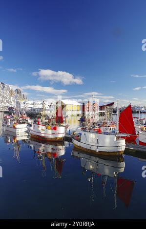 Barche da pesca con vele rosse che giacciono tranquillamente sulla banchina, riflesse nell'acqua, circondate da montagne innevate, pesca, Lofoten, Svolvaer, Nordla Foto Stock