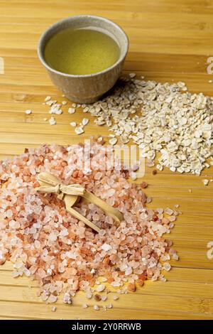 Una foto da studio a spiovente di una pila di sale marino dell'himalaya con una paletta, una pila di avena secca e una piccola ciotola con olio d'oliva Foto Stock