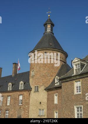 Vista dettagliata di una torre del castello fatta di mura in mattoni con merlature e bandiere sotto un cielo azzurro, Anholt, Renania settentrionale-Vestfalia, Germania, Europa Foto Stock