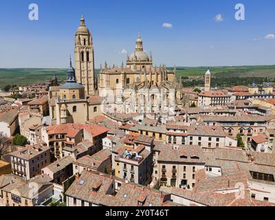 Vista di una città medievale con una chiesa prominente ed edifici storici annidati in un paesaggio sotto un cielo azzurro, vista aerea, cattedrale, Segovia, Foto Stock