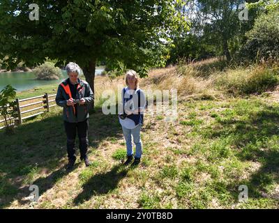 Un uomo controlla un joystick per guidare un drone, con una donna accanto a lui che tiene una telecamera, in vista aerea Foto Stock