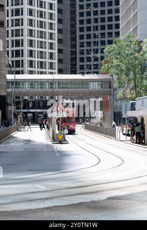 Hong Kong, Cina - 3 luglio 2024: Un tram rosso con passeggeri attende all'incrocio di Hong Kong, in Cina, sotto un cavalcavia pedonale. Foto Stock