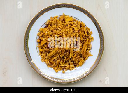 Spuntini piccanti Bombay Mixed Chanachur su un piatto bianco. Vista dall'alto del Bangladesh Crispy snack Bombay o Ruchi Classic Chanachur. Foto Stock