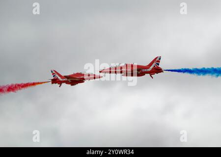 Celebrando il loro 60° anno di operazione due Hawker Siddeley Hawk Jets della RAF britannica Red Arrows squadra di esibizione acrobatica eseguono un cross over Foto Stock