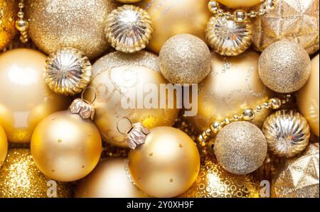 Sfondo natalizio con baule e ornamenti dorati luccicanti. Primo piano di decorazioni natalizie dorate in pile di diverse dimensioni, tonalità e texture. Foto Stock