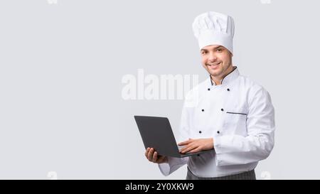 Chef Man Using Laptop Standing On White Studio Background, Panorama Foto Stock