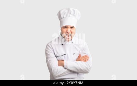 Arrabbiato Chef uomo grida attraversando le mani in piedi in studio, Panorama Foto Stock