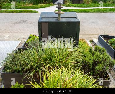 Contenitori per rifiuti con sistema di stoccaggio sotterraneo in strada circondati da piante per rendere le città più ecologiche e moderne Foto Stock