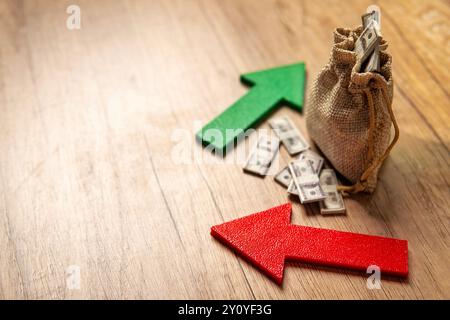 Un sacco pieno di banconote da un dollaro tra una freccia verde verso l'alto e una freccia rossa verso il basso. Fluttuazioni degli investimenti, volatilità del mercato, Foto Stock