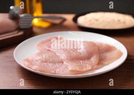 Fare schnitzel. Piatto con carne cruda su tavola di legno, primo piano Foto Stock