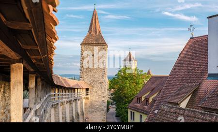 I visitatori di Rothenburg ob der Tauber passeggiano per le pittoresche strade, ammirando le antiche torri e gli affascinanti tetti sotto un cielo blu, immergendosi nella ricca storia e bellezza della città. Foto Stock