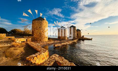 Vecchi mulini a vento sul mare al tramonto sull'isola di Chios, Grecia. Evocano tranquillità e nostalgia in questa pittoresca scena costiera. Foto Stock