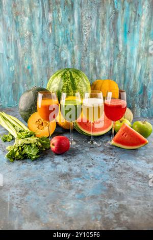 L'anguria e il melone bevande fresche spremute nei bicchieri. La bevanda si trova su uno sfondo blu con un melone a metà anguria, sedano e mela nel backgro Foto Stock