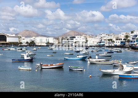 Spagna, Lanzarote, Isole Canarie, Areccife: Veduta della zona portuale principale con uno sfondo di montagne e edifici moderni con piccole barche dentro Foto Stock