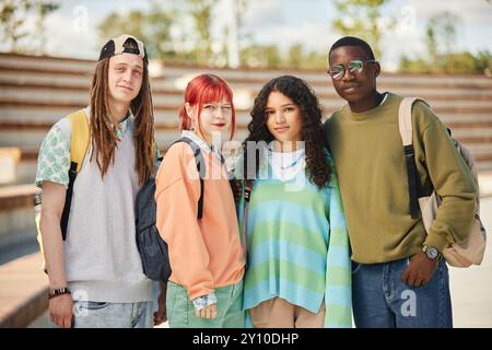 Ritratto di quattro studenti delle scuole superiori di diverse etnie in abiti vivaci, scattato mentre camminavano all'aperto mentre gli adolescenti posano e guardavano la macchina fotografica Foto Stock