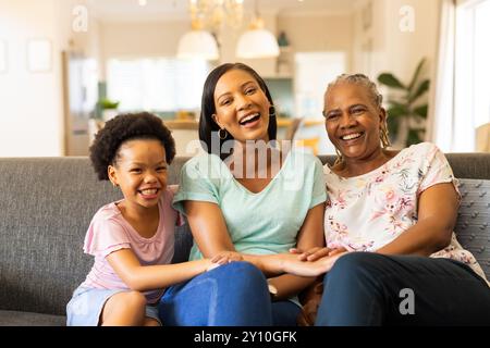 Famiglia sorridente e multigenerazionale seduta sul divano, godendo del tempo di qualità insieme Foto Stock