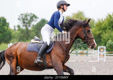 Una donna guida con fiducia un cavallo durante una gara equestre in un'arena all'aperto Foto Stock