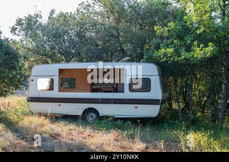 una carovana di camper danneggiata e abbandonata in una foresta Foto Stock