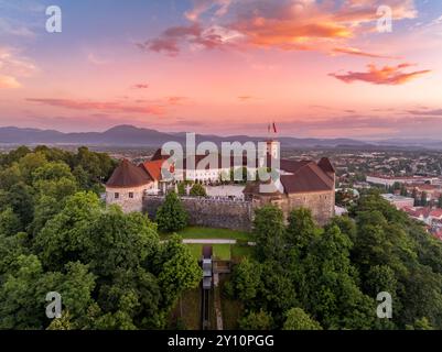 Vista aerea al tramonto del castello di Lubiana in Slovenia , torri, bastioni, funicolare che porta i visitatori su per la collina con il cielo colorato Foto Stock