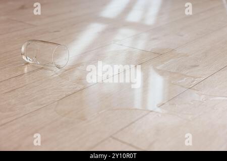 Bicchiere con bibita versata su pavimento in legno Foto Stock