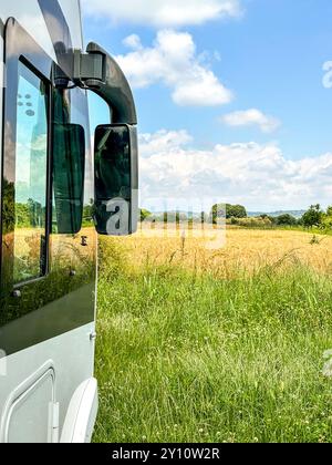 Vista laterale del moderno parcheggio per camper in mezzo a un camper nel verde della natura libera, luogo panoramico e vista del paesaggio. Viaggio in libertà, vacanza in casa alternativa, stile di vita vanlife Foto Stock