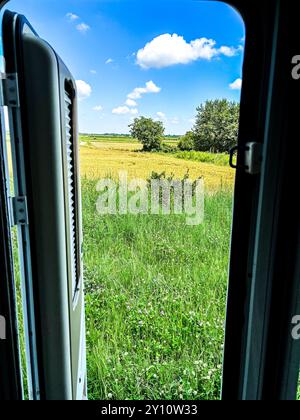 Vista dall'interno del moderno parcheggio camper in camper nel verde della campagna, luogo panoramico e vista del paesaggio. Viaggio in libertà, vacanza in casa alternativa, stile di vita vanlife Foto Stock