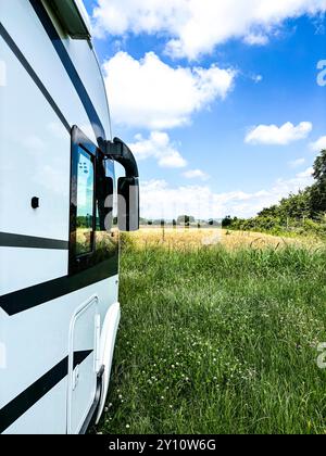 Vista laterale del moderno parcheggio per camper in mezzo a un camper nel verde della natura libera, luogo panoramico e vista del paesaggio. Viaggio in libertà, vacanza in casa alternativa, stile di vita vanlife Foto Stock