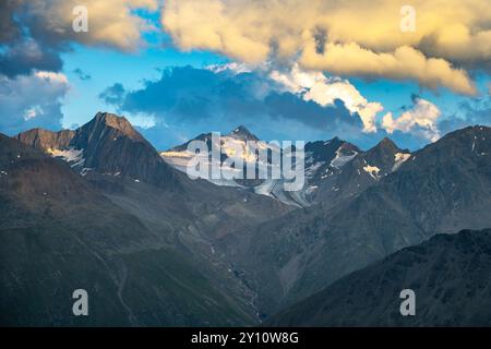 Le splendide vette delle Alpi si innalzano drammaticamente contro un cielo vibrante durante il crepuscolo serale. La luce del sole proietta ombre morbide sui paesaggi rocciosi, evidenziando la bellezza dello splendore incontaminato della natura. Foto Stock